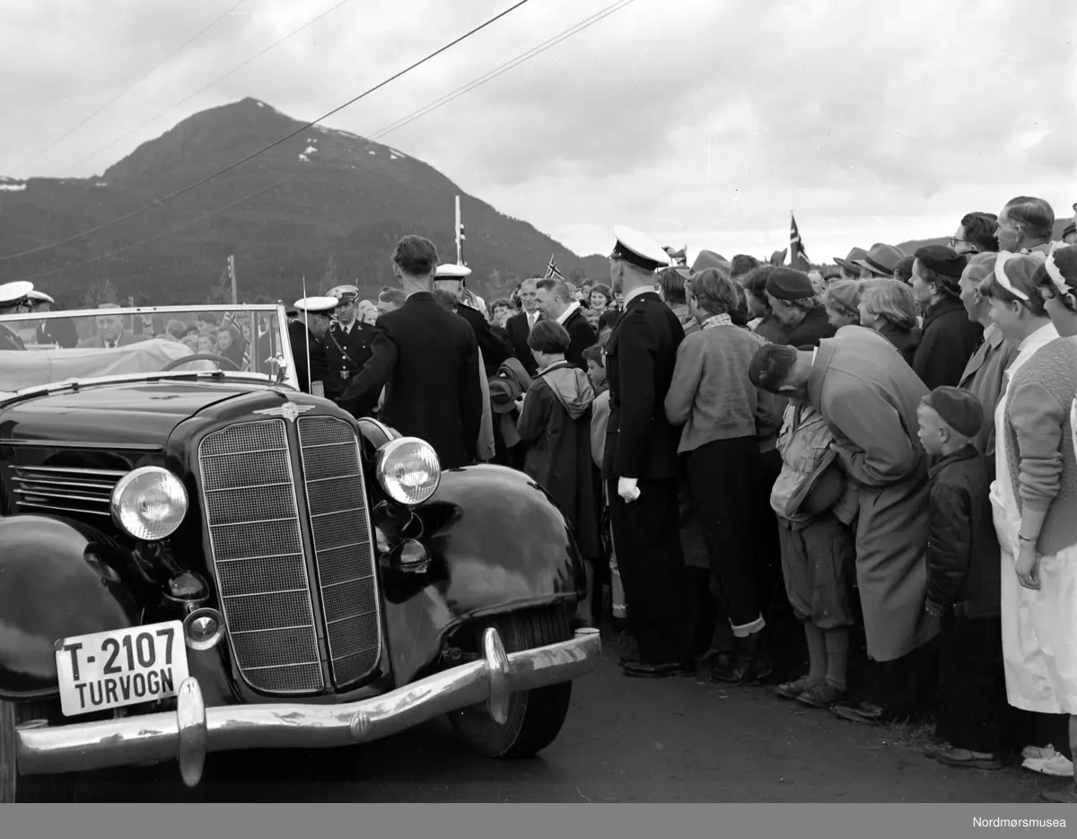 Bilen er en Buick 1935. (Info: Ivar Stav) - Foto fra 1000-årsjubileet for slaget på Rastarkalv. Slaget på Rastarkalv var et slag i 955 mellom Eirikssønnene og Håkon Adalsteinsfostre. Eirikssønnene ledet en hær som bestod av norske og danske vikinger, tildelt av den første danske kongen, Harald Blåtann. Håkon Adalsteinsfostre vant slaget og tvang danskene til retrett. (Kilde: Wikipedia). Bildet er datert 1955. Fotograf er Nils Williams. Fra Nordmøre museums fotosamlinger.