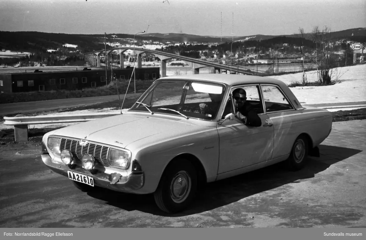 Stig Nahlbom, journalist på Expressen, poserar invid en Ford Taunus på Alnö. I bakgrunden Alnöbron och radiomasterna i Ljusta.