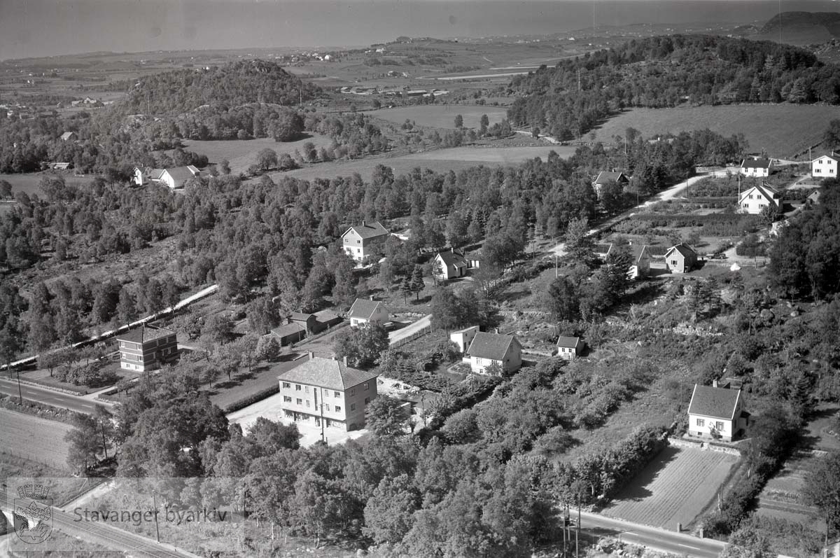 Stavanger ytre. Gausel. Mot S.V...Gausel Kolonial..Veier: Gauselveien i forgrunnen. Dykjelbakken fra den og opp til Gauselbakken. .Gårdsbruket bak til venstre tilhørte Knut Gausel..Murhuset i forgrunnen til venstre tilhørte Fritz Eckhoff..Gausel kolonial til høyre for Dykjelbakken var drevet av hans datter.Det store huset midt på bildet eid av Tønnes Gausel.Til venstre for Dykjelbakken finner vi to små hus. Det nederste eid av Agnes Eckhoff, det oppfor av Anny Gausel.