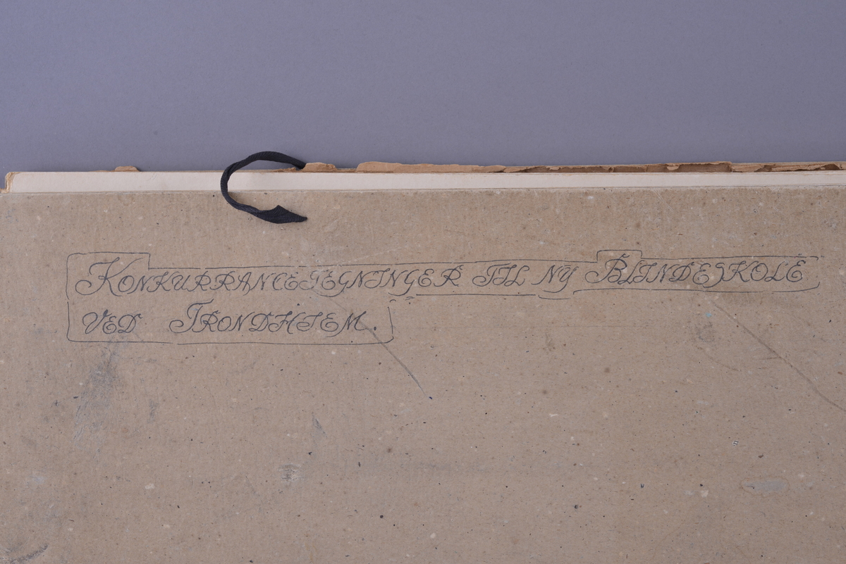 Mappe med materiale som omhandler tegnekonkurranse. Består av mappe (01), Konvolutt (02), visittkort (03-04), hefte (05), ark (06), og tegninger (07-19). 

Mappe i grovkornet kartong med tråd for knyting. Inne i mappa ligger 13 rektangulære tegninger. Tegningene er laget på hvitt papir som er limt på kartong. Noen tegninger er fargelagt, noen er i svart-hvitt. Sammen med tegningene ligger det et hefte av papir med trykt svart skrift fra komiteen som omtaler alle bidragene og vinneren, et ark med beskrivelse av det ene bidraget, samt en liten konvolutt med vokssegl som inneholder to visittkort.