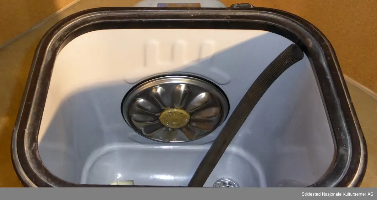 Elektrisk vaksemaskin i emaljert metall. Lokk i aluminium, gummislange morknet(knekt). Maskin med varmeelement som varmer opp vannet. Sluk i bunn av tank. Motor plassert under vanntank. Evalet logo i messing med vinger, plassert i front av maskin. Står på fire føtter, gummierte. Svart gummipakning i topp av maskin. Grep til lokk mangler. Består av 4 deler. Vaskemaskina hadde opprinnelig vrider som kunne monteres på toppen, denne kunne tas av og på. Denne har blitt kastet av giver (morknet)