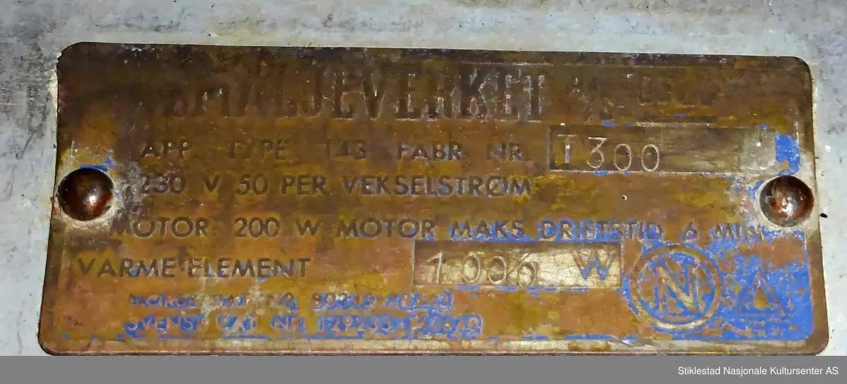 Elektrisk vaksemaskin i emaljert metall. Lokk i aluminium, gummislange morknet(knekt). Maskin med varmeelement som varmer opp vannet. Sluk i bunn av tank. Motor plassert under vanntank. Evalet logo i messing med vinger, plassert i front av maskin. Står på fire føtter, gummierte. Svart gummipakning i topp av maskin. Grep til lokk mangler. Består av 4 deler. Vaskemaskina hadde opprinnelig vrider som kunne monteres på toppen, denne kunne tas av og på. Denne har blitt kastet av giver (morknet)