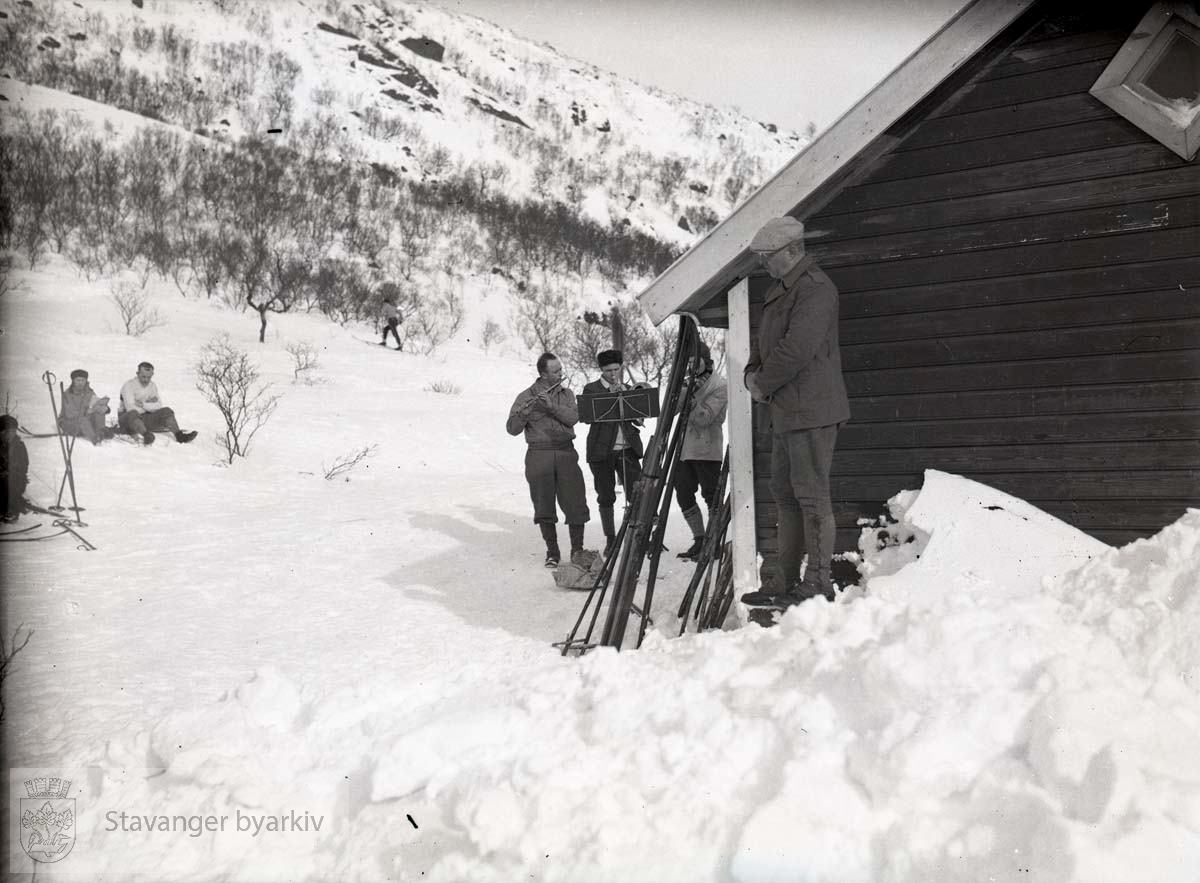 Ski og skigåere utenfor hytte.