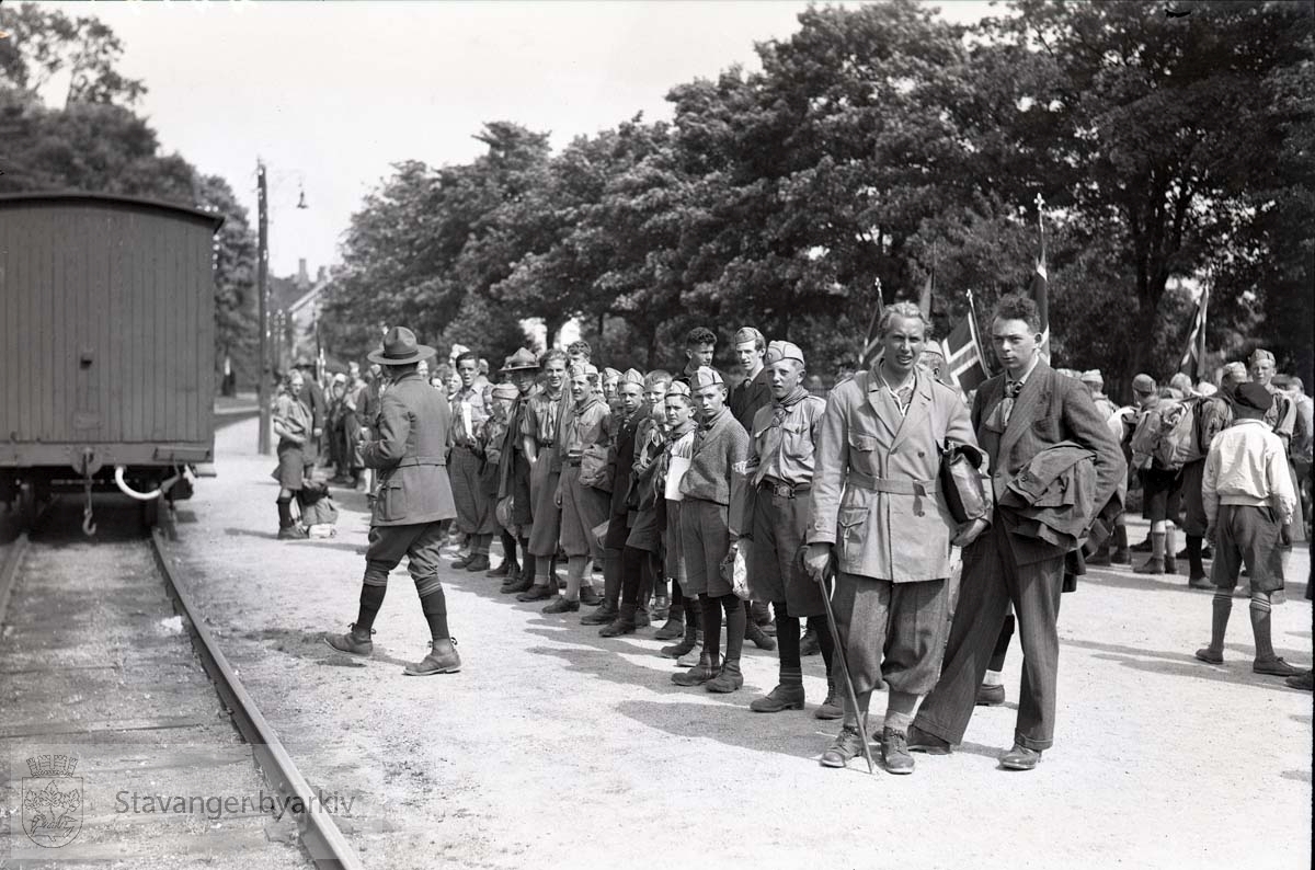 Avreise med toget. Speidere og leirdeltakere står oppstilt og venter på toget.