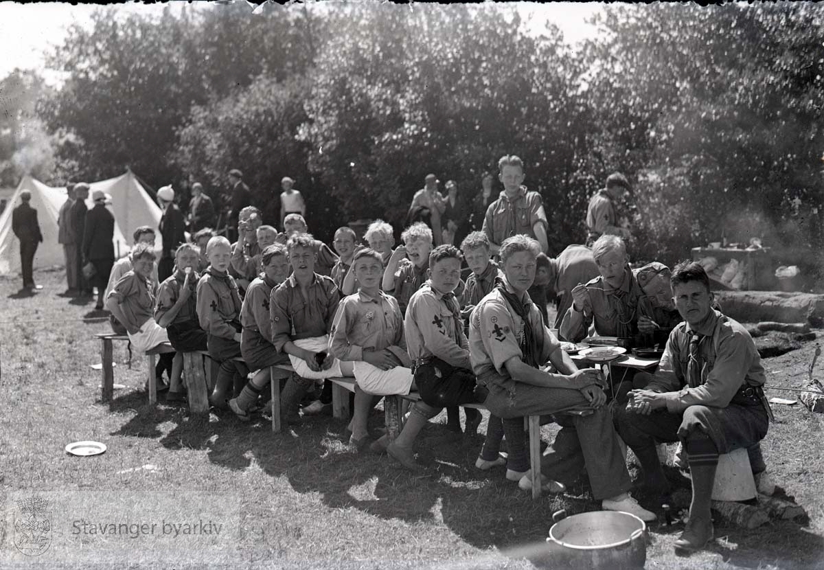 Speidere har måltid i leiren. Telt i bakgrunnen.