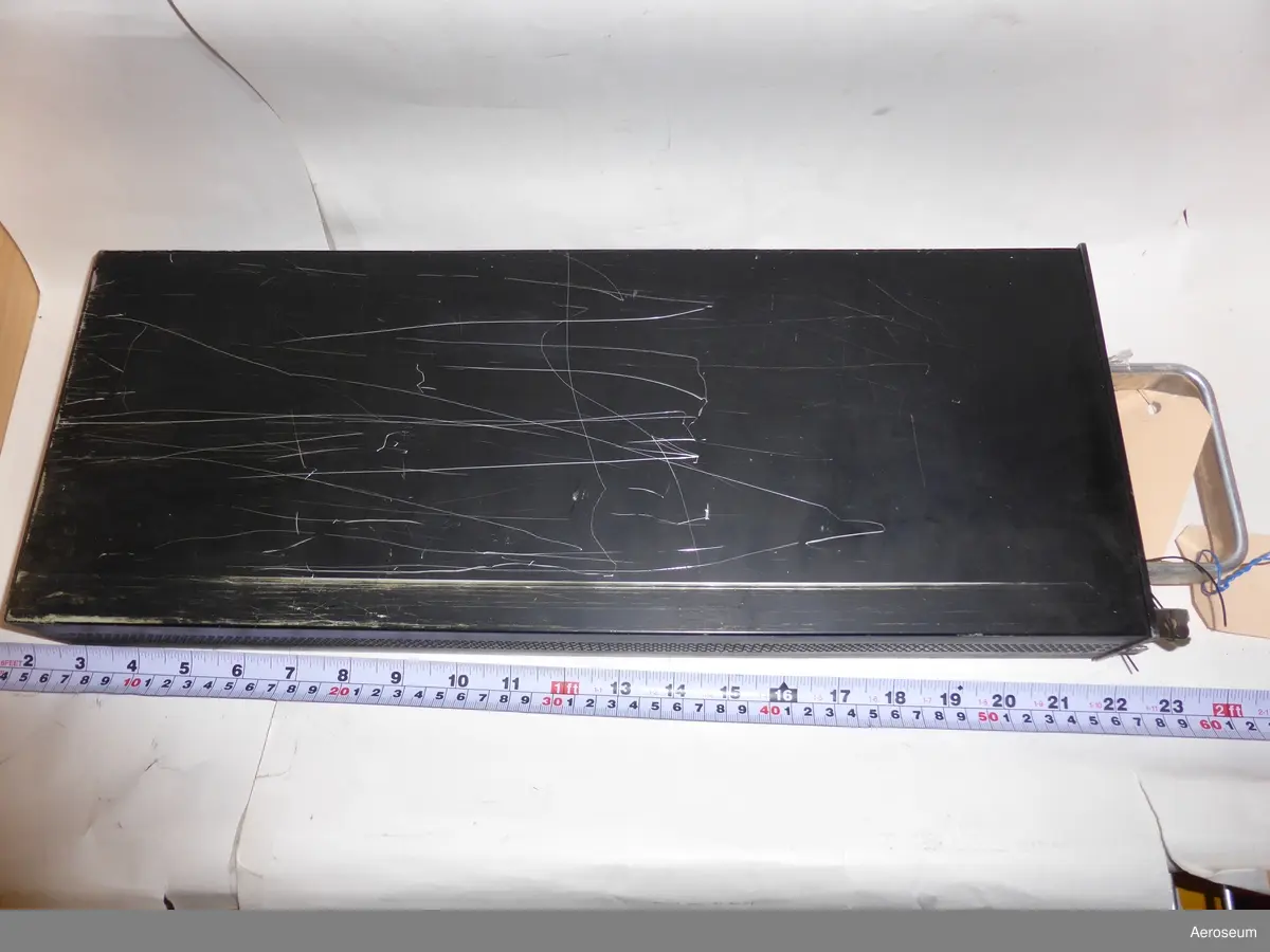 En flight log computer, (Svarta lådan). Tillverkad av The Decca Navigator Company Ltd. Gjord i svart metall. Den är sliten, det finns skrapmärken i metallen.

På ena sidan står det: "FLIGHT LOG COMPUTER TYPE 1732 SER. NO. 095 WR 649 CSD 27 INS. INPUT 22-29 V.D.C. A.V. MOUNTINGS REQUIRED THE DECCA NAVIGATOR CO. LTD. LONDON. MADE IN ENGLAND".