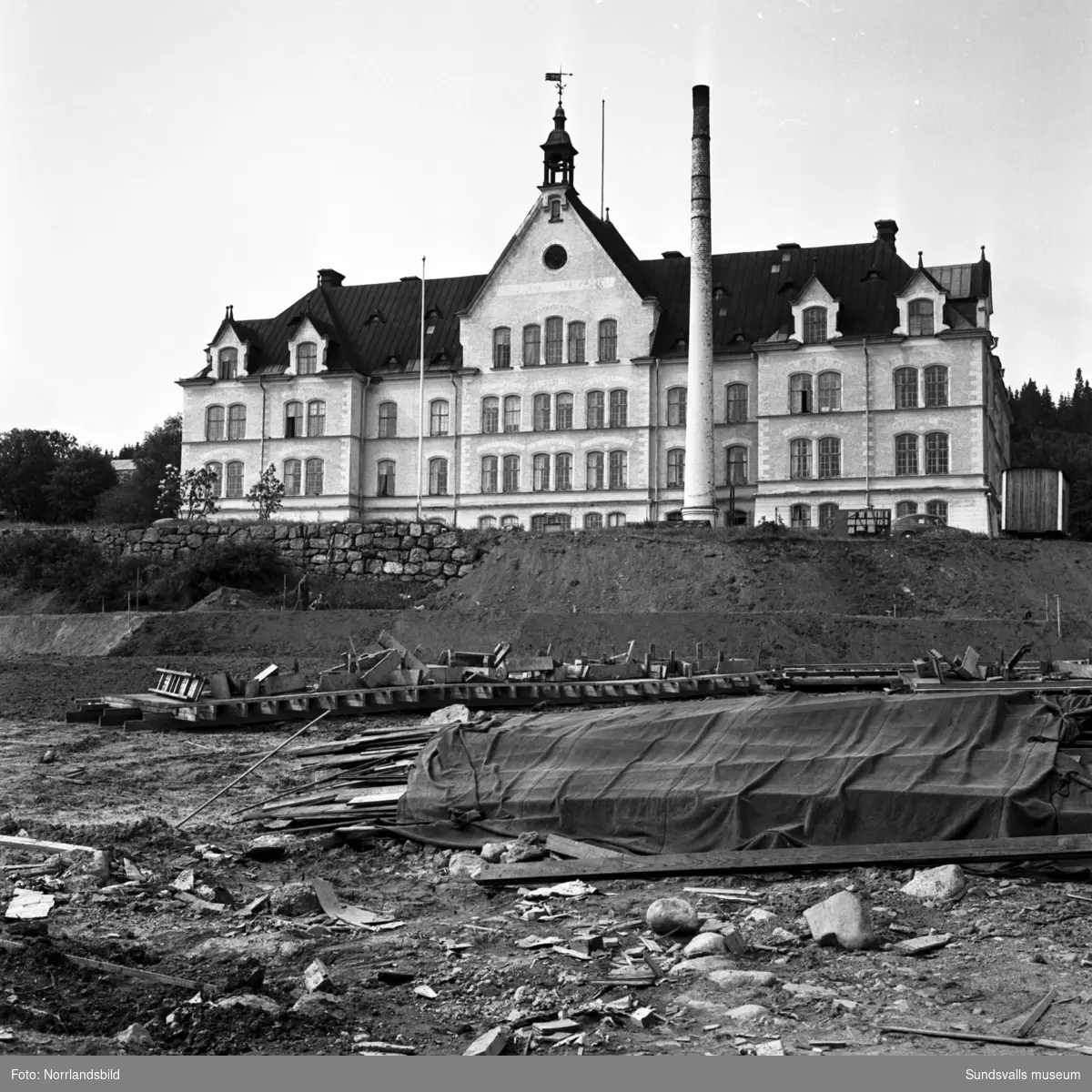 Exteriörbilder av Birstahemmet, Sköns försörjningshem, ett par år innan det rivs. I förgrunden pågår markplanering för industriområdets utbredning.