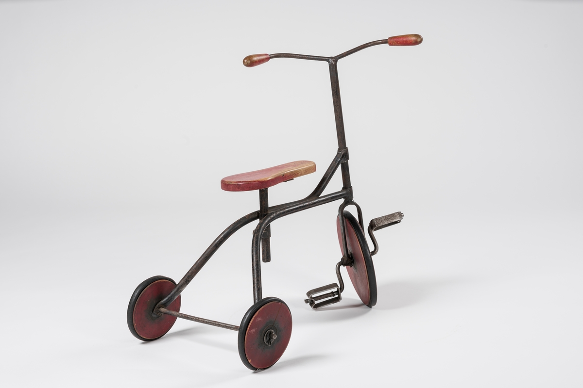 Form: Ramme av hulrør, forhjul med pedaler, flatt, innsvinget sete.
