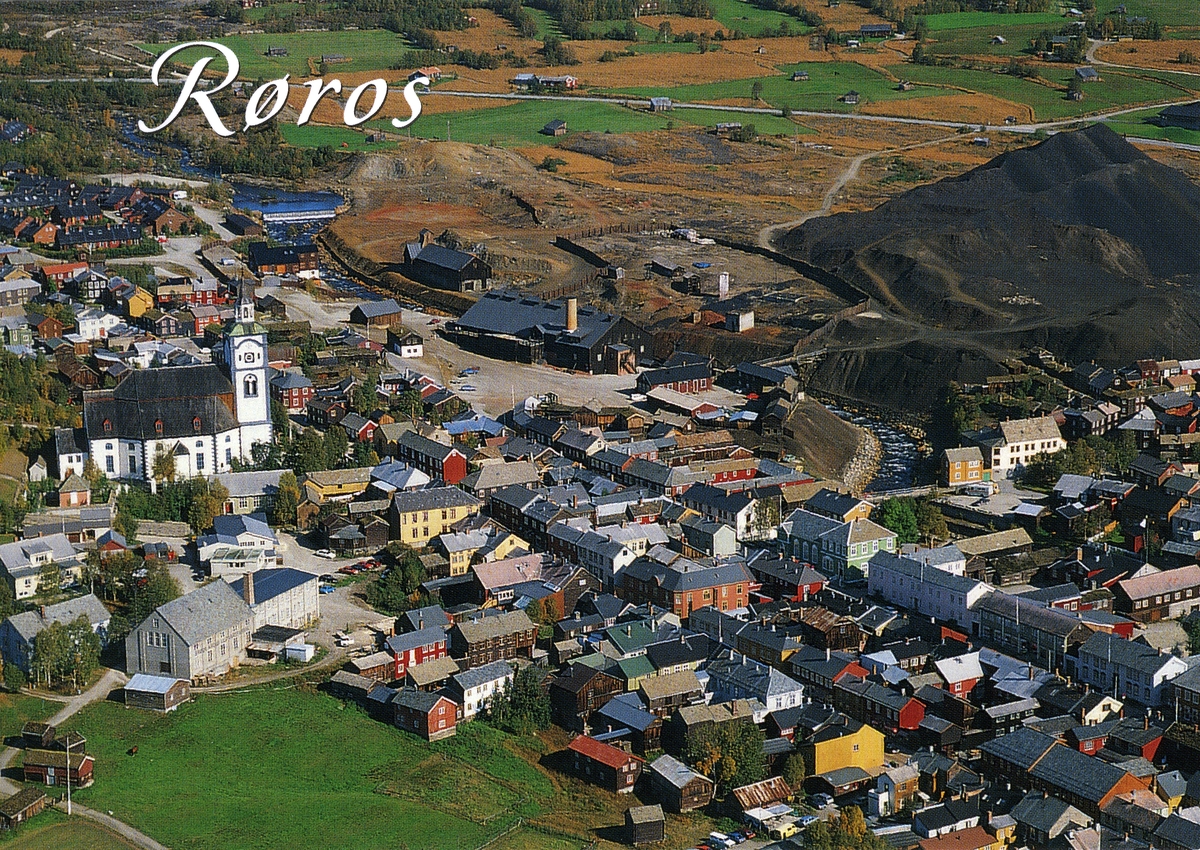 Flyfoto av kjerka og øvre del av gatene på Røros. Hyttdammen, røstplassen, Malmplassen og slagghaugan i bakgrunnen. Postkort