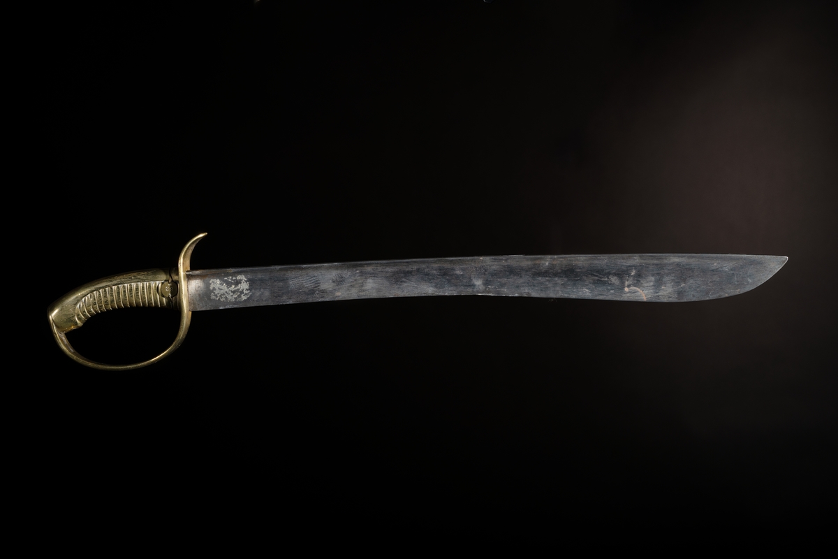 Huggare m/1846 för skeppsgossekåren med eneggad klinga av stål, Hafströms konstruktion. Fäste helt i mässing med räfflad kavel och parerstång som övergår i handbygel. Märkt : "1:C 86" instansat på parerstången, samt "82" instansat på en liten rund mässingsbricka, fästad med mässingstråd runt kaveln.