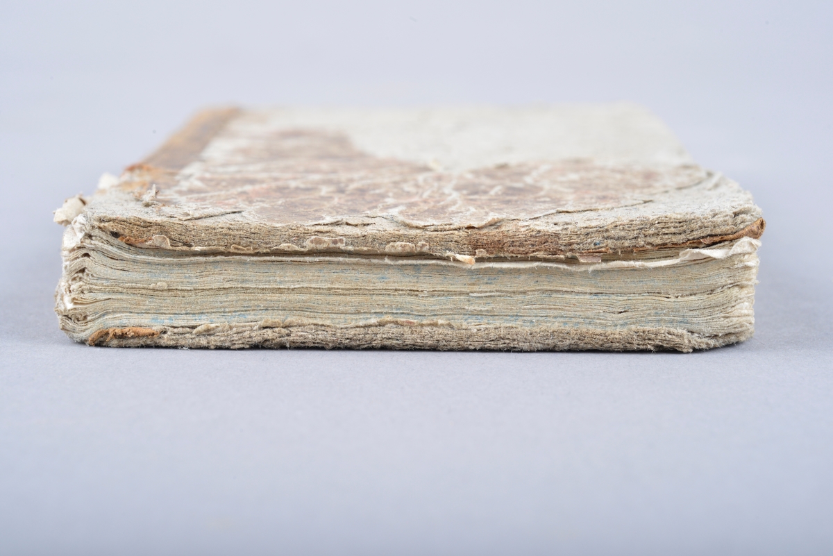 Innbudet bok. Boken er et halvbind med skinn på bokryggen. Marmorert omslag. Håndskrevet tekst på for- og ettersats. Det er også utydelige ord og bokstaver skrevet med blekk og blyant. To tegninger på forsatsen. Disse tegningene er trolig tegnet av barn og viser en ung jente med kjole og en gammel dame med en stokk.