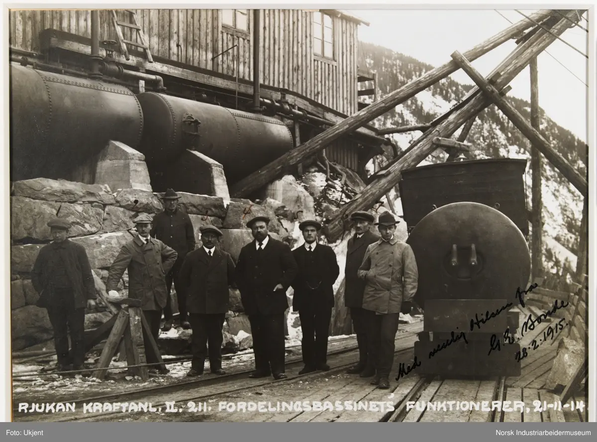 Innrammet foto. Funksjonærer på Norsk Hydro stående foran fordelingsbassenget. Rjukan Kraftanlegg II, Såheim.