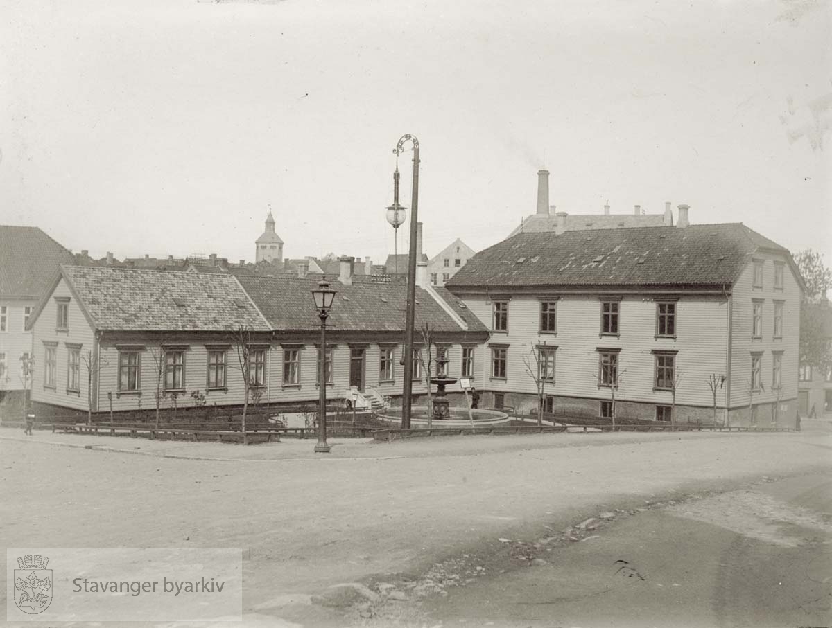 Bibliotek, formannskapskontor og kemnerkontor (tidl. Kombinerede Indretning) på St. Peters plass. Valbergtårnet skimtes i bakgrunnen. Lyktestolper i forgrunnen. .Jernfontene.