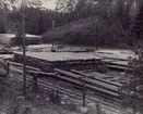 Björkhult Impregneringsanstalten. Upplaget av färdiga stolpar. I bakgrunden Järnvägslinjen Linköping - Hultsfred. Impregneringsanläggningen är belägen i närheten av Björkhults station på nämnda järnväg.