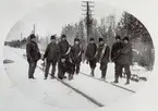 Trådsträckning 1925 vid banskillnaden i Ljusdal. Platsen kallades så därför att järnvägsspåren mot Bollnäs och Hudiksvall skildes där. De stående personerna är från vänster, Lindberg, Johan Thorell, okänd, Gustaf Nordahl, Johan Larsson ( Wia-Lasse), Sören Eriksson, Alfred Andersson och Clas Wennberg. Stående på knä framtill med lödugn är Hedberg.