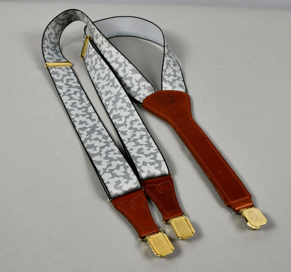 Bukseseler med krystallmønster i grått med skinnbeslag og metallspenner. Logo for Lillehammer '94 på skinnbeslaget på ryggen.