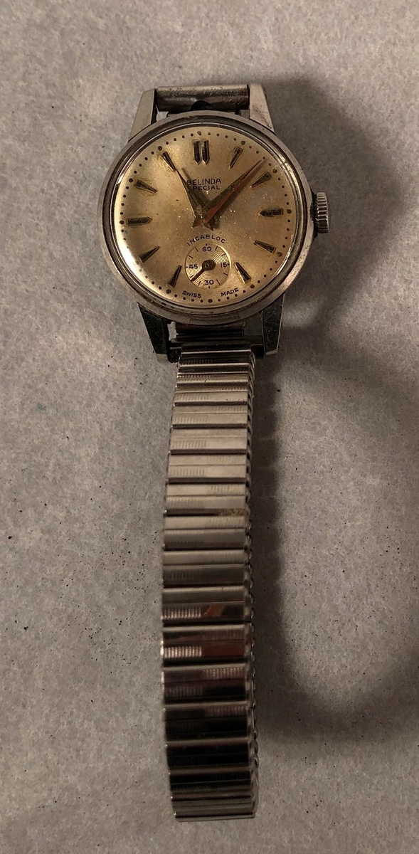 Klokke av stål med lenke med sekundviser (runding). Trekkes.