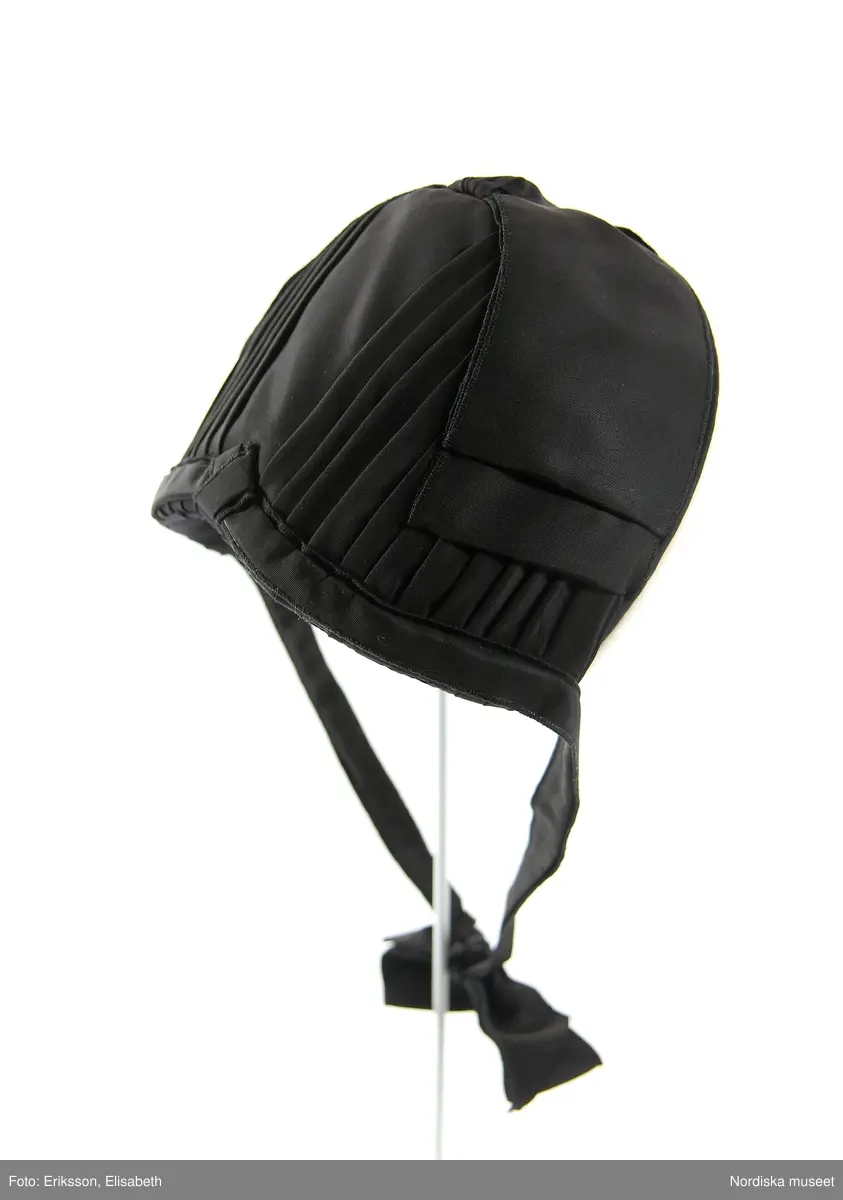 Svart hatt (nackhatt) som ingått i uniform/arbetsdräkt för kvinnlig överkonstapel vid svenska fängelser. Detta är en kopia tillverkad 1991, av äldre typ av hatt. Framkanten kantat med vitt bomullsband.
/Cecilia Hammarlund-Larsson 2009-08-31