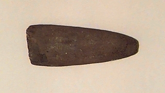 Runt tvärsnitt, den ena eggbildande sidan dock relativt planslipad långt uppåt mot nacken. Avsmalnar mot nacken. Eggen skadad.