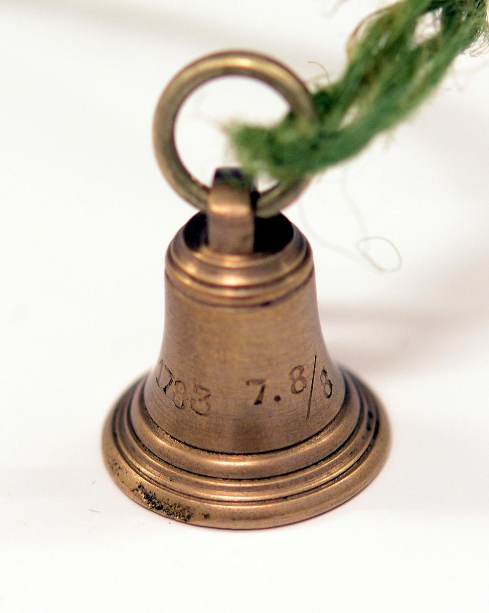 Signet av bronse, med initialene H.I. i dekorativ inngravering og ring rundt, støpt av Skiens gamle kirkeklokker, i klokkeform med feste på toppen og ring i. Medfølgende notat fra giveren til museet.