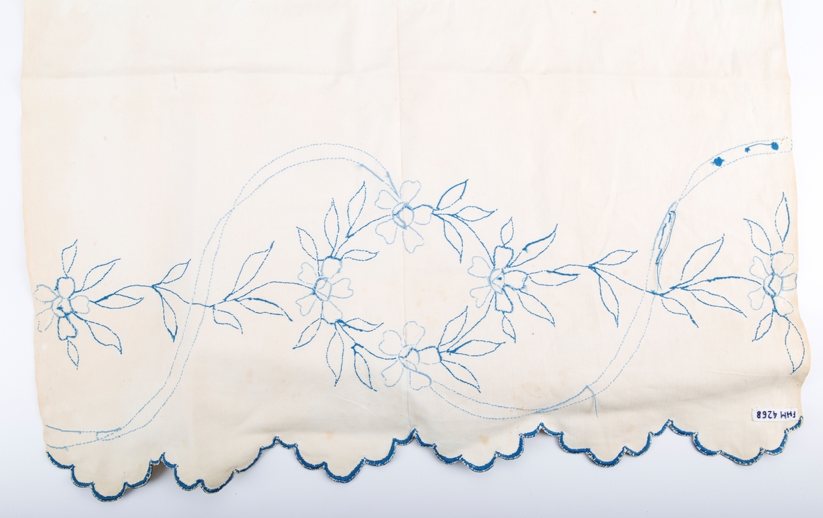 Vevet med blått konturstingsbroderi. Motiv; Blomster og ranker- Blåbroderte tunger i hver ende. Fabrikkert