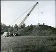 Badelunda sn, Anundshögsområdet, Långby.
Kranbil lyfter upp något på toppen av Anundshögen.