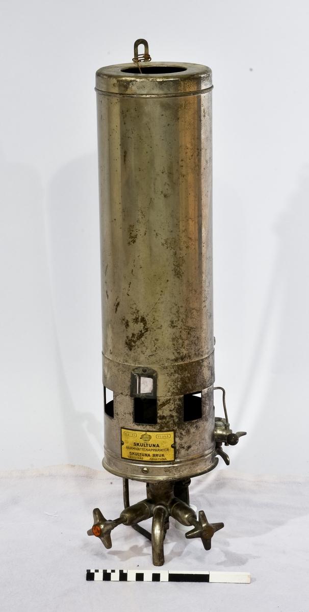Varmvattenberedare i metall med texten "Har texten " 1607 Skultuna, Varmvattenapparater, Aktiebolaget Svenska Metallverken, Skultuna, Västerås Sverige" på sig, samt två nr: MT 12, 77075.