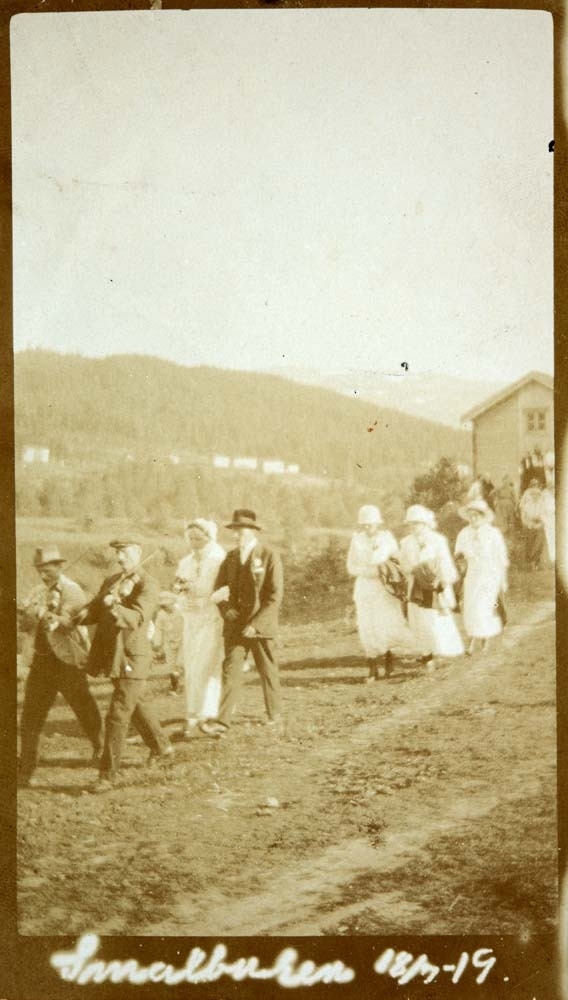 Brudemarsj med felespillere, brudepar, og brudepiker.
Brudeparet er Jenny Olea Pedersdatter og Ingvald Kristoffer Lund Hyttebakk. De giftet seg 1920