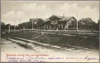 Stationsområde med vy på bangård och hotell vid sekelskiftet.