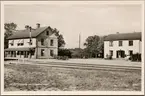 Stationshus och postkontor med del av bangård i bild.