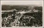 Flygfoto på samhälle med järnväg och fabrik.