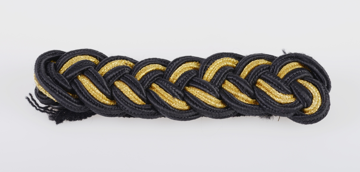 En hatteboks (FTT.56303.01) som inneholder en snutehatt (FTT.56303.02), et bandolær (FTT.56303.03) og en epålett (FTT.56303.04).  
FTT.56303.01:
Hatteboksen er laget av blikk og er svartlakkert utenpå. Lokket er hengslet på baksiden. Oppå lokket er det et enkelt håndtak. I fronetn er det en hempe for hengelås. Den har to lave bein som er laget av sammenrullet blikk. Boksen har form tilpasset hatten. Esken har ikke fôr, men det ligger et papir i bunnen.
FTT.56303.02:
En svart uniformshatt, nærmere bestemt en snutehatt eller en tosnutet hatt. Det er gullbånddekor på hver snute. På den ene siden er det festet en stor kokarde i rødt, hvitt og blått. Over denne er det to flate gullbånd som ender i en spiss. I enden er det en gullfarget metallknapp med et anker med en kongekrone over. Hatten er laget av svart silkefloss med svarte silkebånd langs kanten. Hatten har hvitt silkefôr og svettebånd av brunt lær. På svettebåndet er det festet brune skinnreimer til å feste under haken. På den ene siden er det festet en hvit silkesløyfe. Silkefôret har informasjon om produsent, se "Påført tekst/merker". Det er også bilde av en edderkoppe og et edderkoppnett. Hatten har avstivning ved hjelp av papp. Hatten er håndsydd.
FTT.56303.03:
Et bandolær laget av svart skinn, svart silkestoff og messing. Midjebeltet har en spenne midt foran. Spennen har motiv av et anker med en krone over. På innsiden av beltet er det sydd fast en skinnreim med metallhull til å regulere livvidden. Skulderreimen er festet i midjebeltet med metallringer. Delene til skulderreimen festes sammen med to fjærbelastende kroker. Ved sammenføyningen skulderreim og midjebelte er det påmontert en liten kjetting med krok.
FTT.56303.04:
En skulderklaff til uniform. Oversiden består av svarte- og gullfargede flettede snorer. På undersiden er det sydd på svart ullstoff som er like bred som klaffen. I den ene enden er det sydd på en svart knapp som ullstoffet kan festes i.