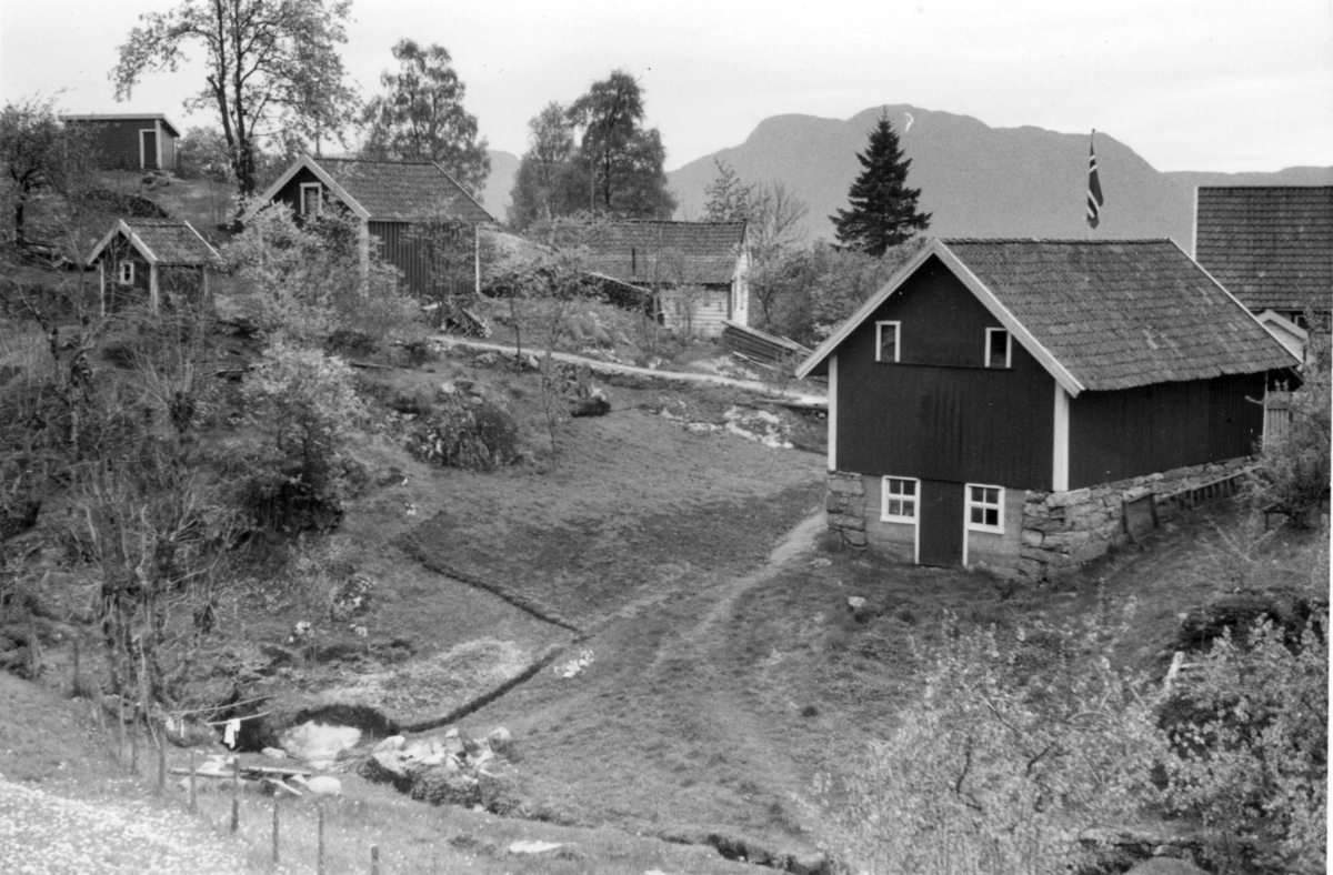 Et gårdsbruk med flere småhus langs Økstrafjorden.