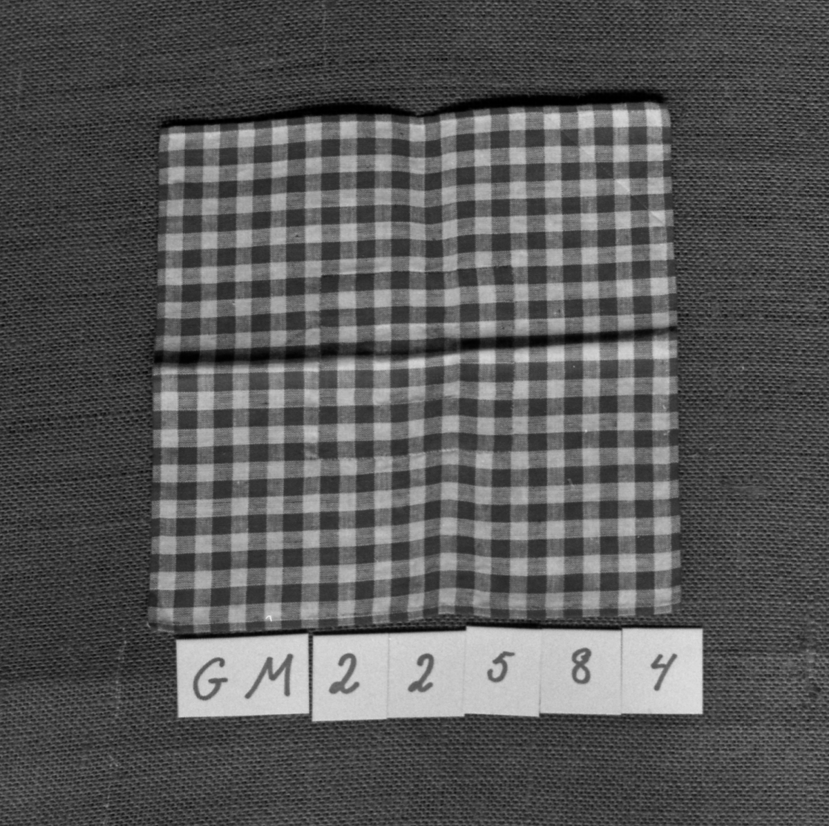 Firkantet tøylapp kantsydd for hånd og med lapp sydd på over hull