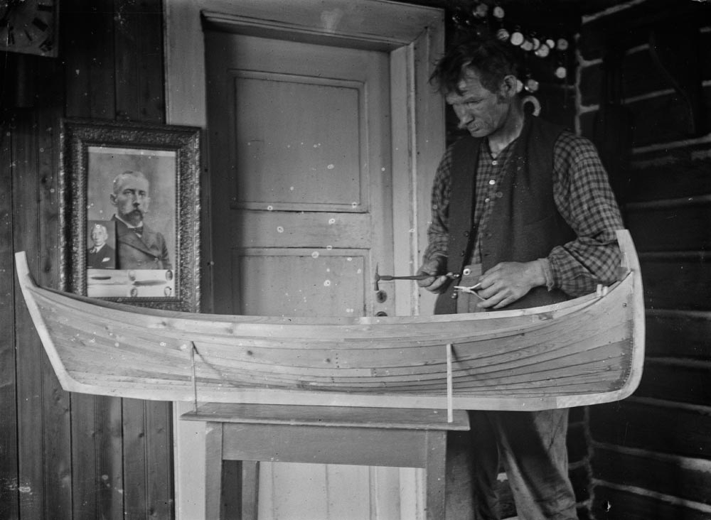 Leirfjord, Ulvangen, Myrvang. Kornelius Myrvang arbeider med modellen av en Nordlandsfembøring i stua på Myrvang. På veggen henger et bilde av Fridtjof Nansen.