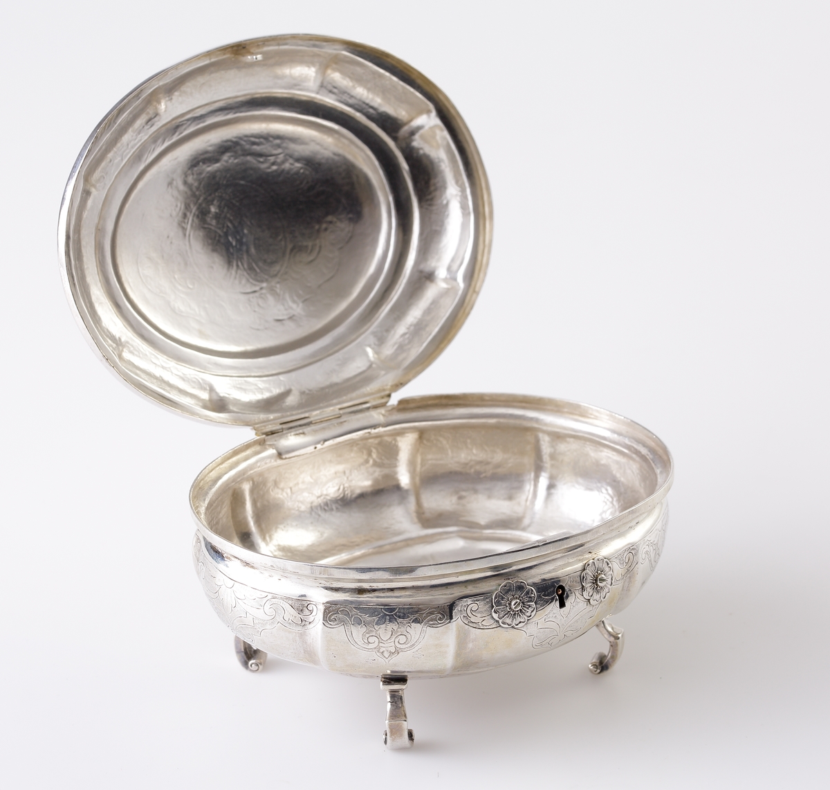 Sockerskrin i silver.
Oval modell. Graverade lambrekäng(?)bårder längs det bukiga livet. Nyckelhålet omges av två blommor i relief (nyckel saknas). Står på fyra inåtvända fötter. På locket ett ornerat spegelmonogram: "AG" (?).  
Stämplar (ofullständiga) + åldermansranka på undersidan av skrinet.