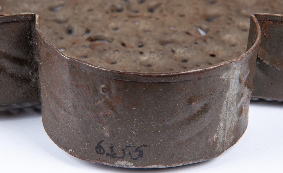 Ostform av plåt med fyra spetsiga och fyra rundade hörn. Genombrutet mönster i botten.
Bredd 22cm.