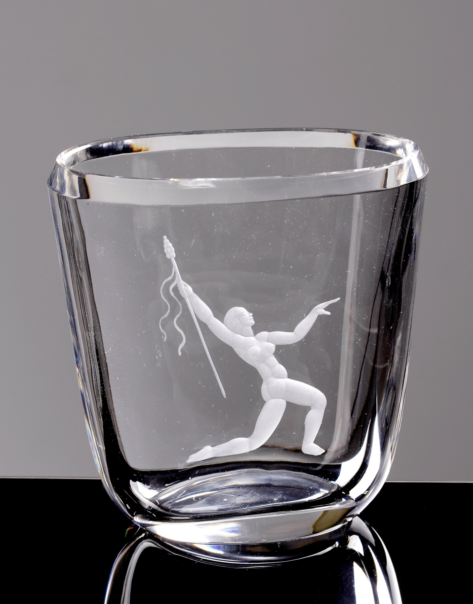 Vas. Oval genomskärning, nedåt avsmalnande. Graverat: knäböjande flicka med spjut. Graverad av *Emil Weidlich, verksam 1929-42.

Inskrivet i huvudkatalogen 1952.