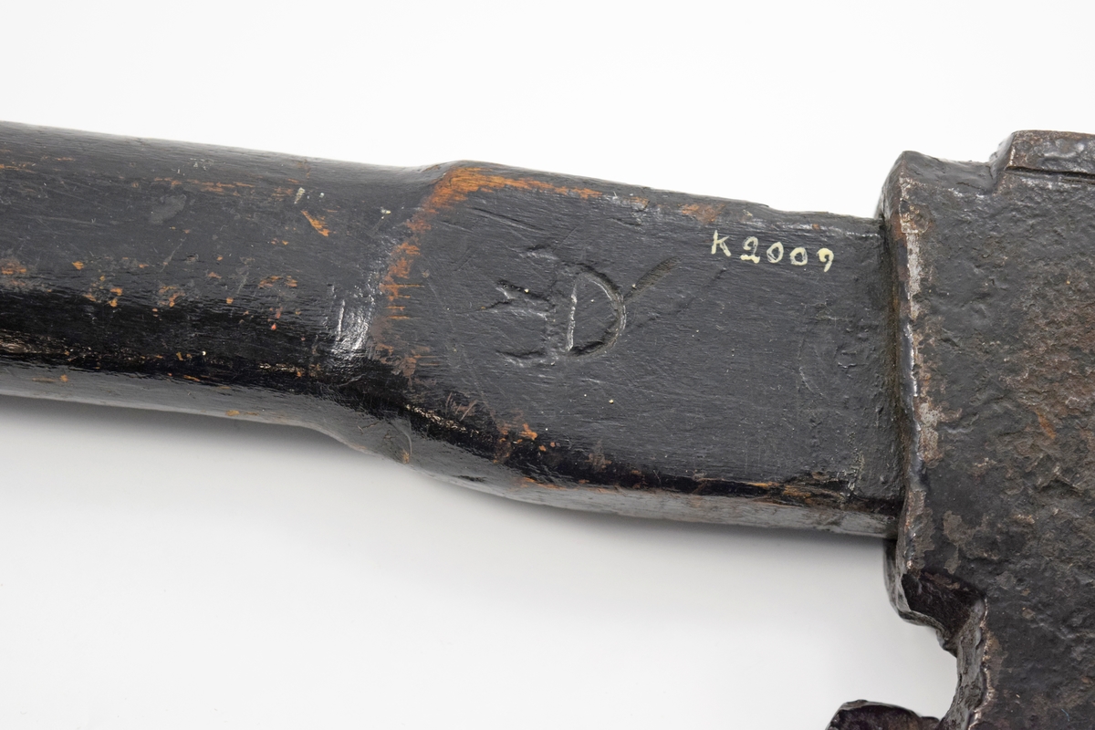 Yxa av stål med träskaft, svartmålad. Såväl yxa som skaft med tre kronstämplar. På skaftets ände en mässingsbricka med nr 524, troligen timlönarens nummer. Härstammar från 1800-talets senare del och har använts av timlönare på örlogsvarvet.