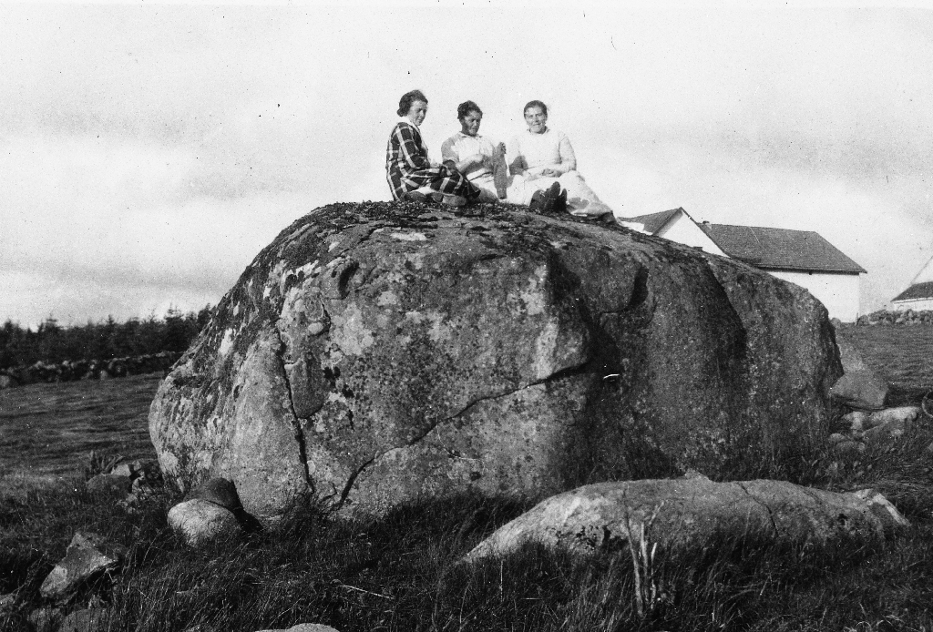 Bygningane på garden til Jonas Lende mest gøymde bak den store steinen. T. v. oppå steinen sit Anna Lende. Dei andre er ukjende. Steinen vart fjerna i 1968.