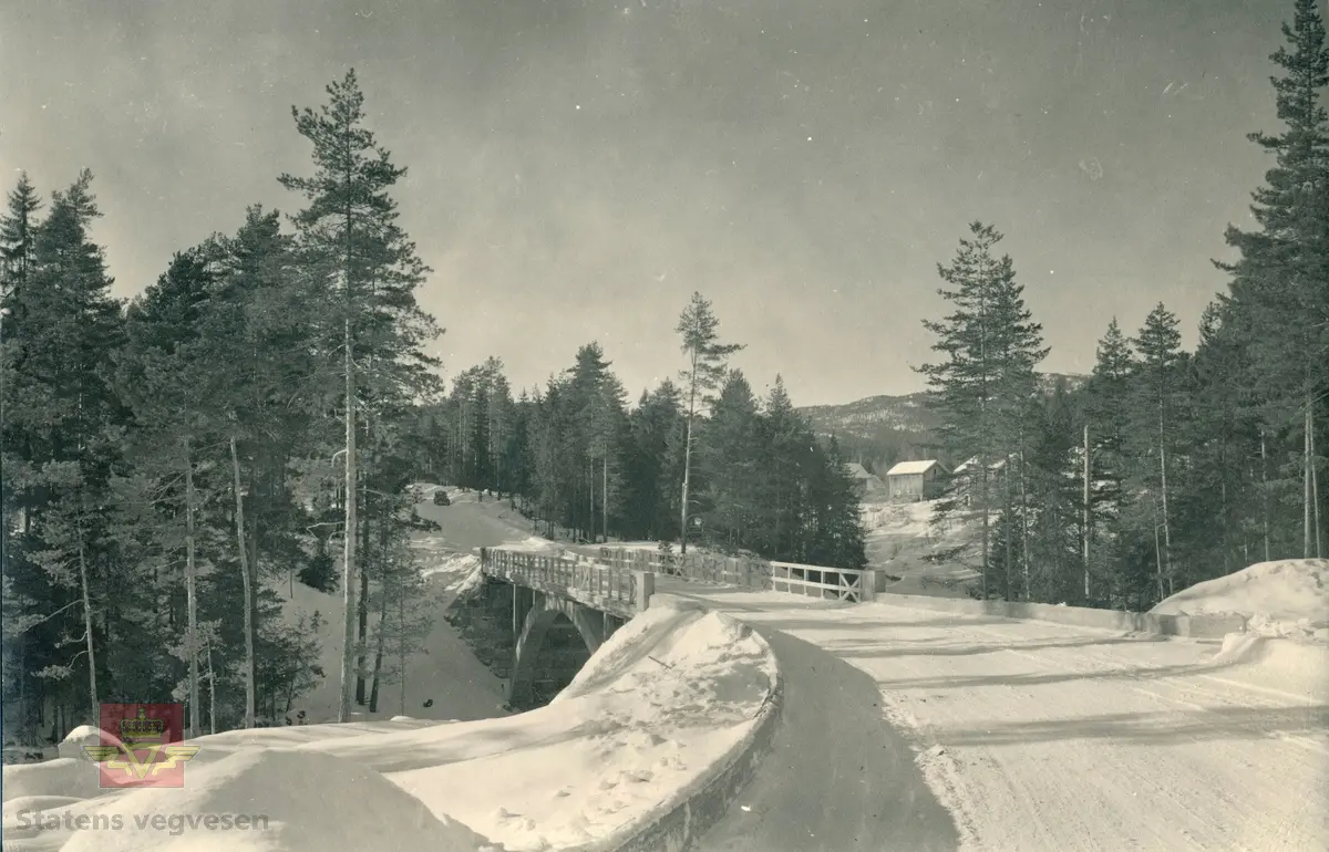 Kvenna bru over Kobberbergelva i Kongsberg. Buebru i betong. Betongbuebru åpnet i 1941. 
Brua ligger i Saggrenda på tidligere E-134. Meheiavegen begynner etter avkjøring inn til Saggrenda, ved krysset Meheiavegen og Bergmannsvegen. Opplysninger fra Svein Julton. 
Etter bilen å dømme på bildet kan det være tatt på 1940-tallet.
