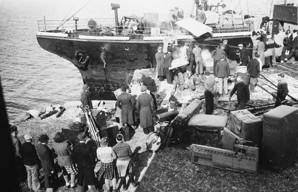 Kaien utanfor arbeidsskulen på Sand. Elevane skal heim etter  endt skuleår. Ein kan sjå pakkar med møbler o.a. som dei har laga på skulen.