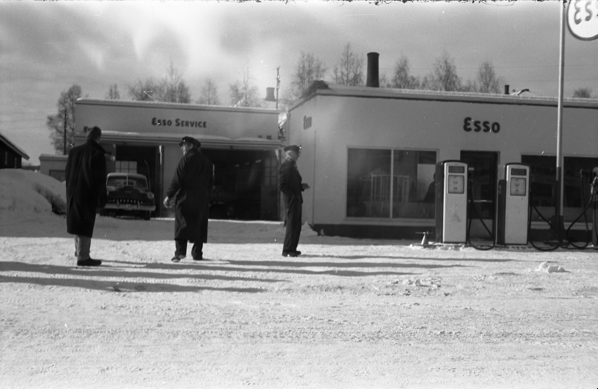 Tre bilder av noen mannfolk ved Esso benstinstasjonen på Lena februar 1958. Helt til høyre på alle tre bildene er muligens Torbrjørn Lundsten, drosjesjåfør fra Kraby, og til høyre for han muligens Paul Grindvoll.
Bilen i bakgrunnen er iflg. informant en drosjeregistrert De Soto årsm. 1951-53.