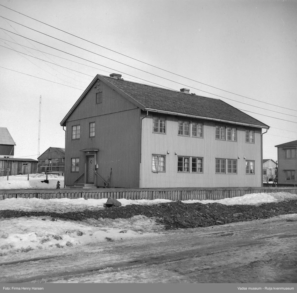 Damsveien 23, Vadsø, 1949. NRKs funksjonærbolig (tidligere Televerkets funksjonærbolig). Bildet er tatt fra Damsveien mot nordøst. Til venstre for boligen ser vi en av kringkastingsmastene og i høyre billedkant deler av det tidligere Elvebakken-huset.