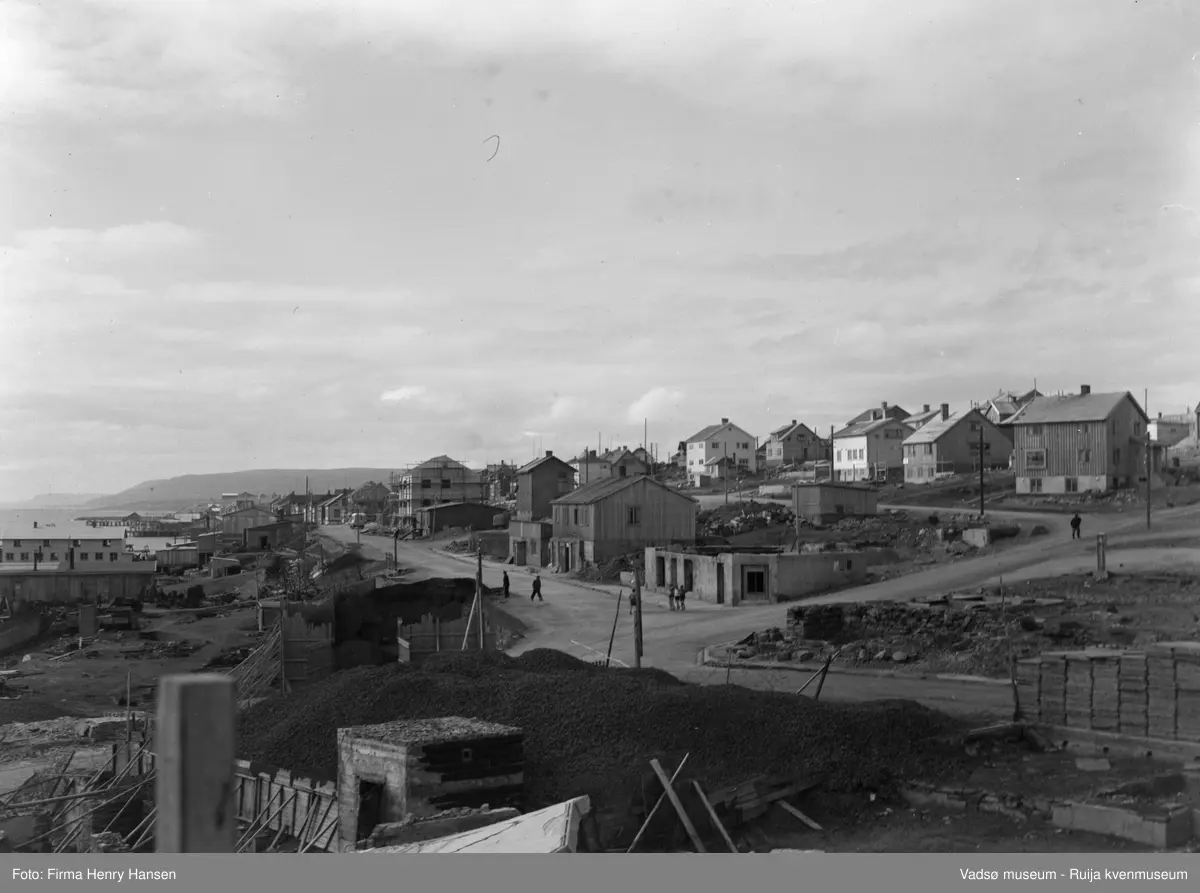 Vadsø Sentrum 1948. Bildet er tatt mot nordvest. Fremst på bildet et stort kullager. Langs Havnegata ses grunnmurer, brakker og gjenreisningshus under oppføring. Nedenfor Havnegata ser vi kaianlegg og fiskebruk langs havna. Langs Nyborgveien flere gjenreisningshus.