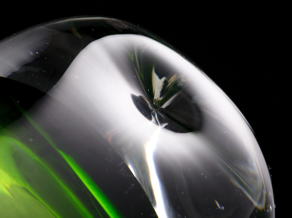 Oval och konisk till formen.
Grönt underfång med tjock ofärgad botten.
På bottens sidor två intryckta markeringar.
Vasen är av sekundakvalité och ofärdig i det att den kullriga bottnen inte planslipats.