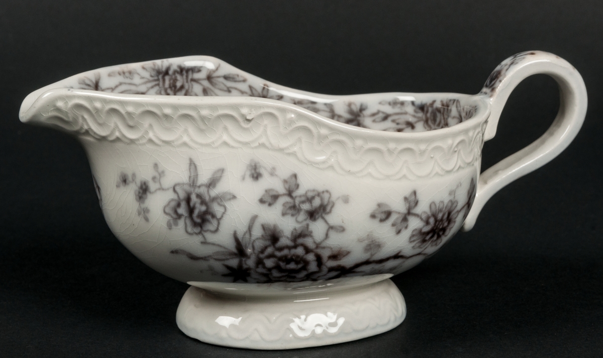 Såssnipa. Dekor Stjärnsund. Koppargravyrtryck i mullbärsbrunt.
Vit massa med brun dekor av blomster.
Bård i godset längs brämet.