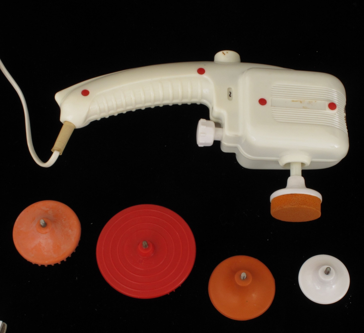 Eske med elektrisk massageapparat. Apparat i gulhvit plast. I alt 5 ulike redskaper.  Lokkets innside med bruksanvisning.