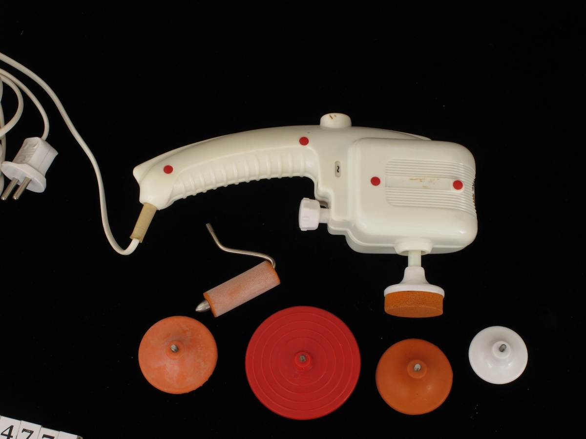 Eske med elektrisk massageapparat. Apparat i gulhvit plast. I alt 5 ulike redskaper.  Lokkets innside med bruksanvisning.