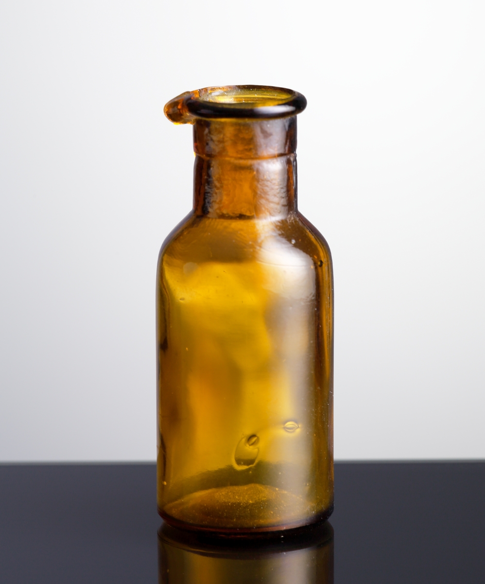 Mindre apoteksflaska med spårad pip.
Brunt glas.